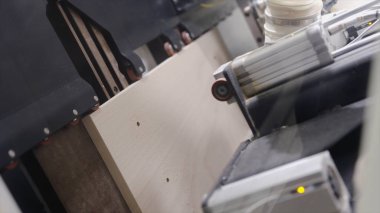 Tahta tahtada delik açan otomatikleştirilmiş makinelere yakın çekim. Başla. Ahşap ürünlerin işlenmesi için endüstriyel girişimde tahta tahtalarda delikler açan makine
