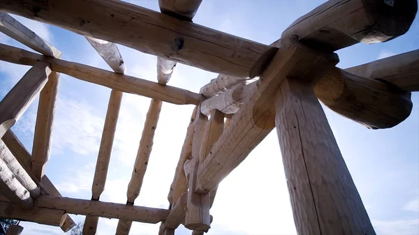 Frame of wooden country house under construction from logs. Clip. Construction of log house in beginning of construction on background of blue sky