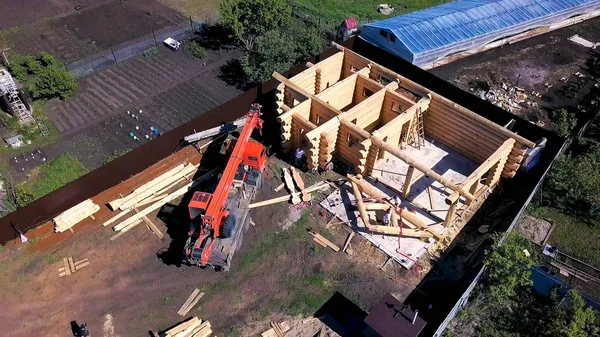 Top view of wooden house under construction. Clip. Top view of country land on which construction of wooden house. Construction of country wooden house with crane on site