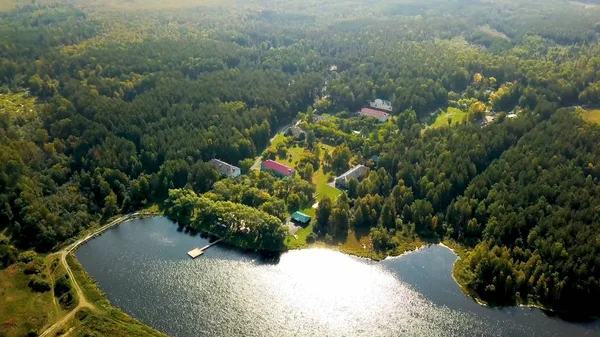 Old country resort in forest by lake. Stock footage. Top view of picturesque recreation center located by lake. Wonderful vacation in countryside in camp in sunny weather