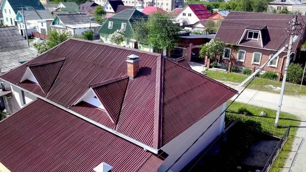 Kır evinin çatısının üst manzarası. Stok görüntüleri. Köyde çok güzel yeni bir ev var. Çatı kestanesi veya koyu kırmızı pahalı ve güzel görünüyor.