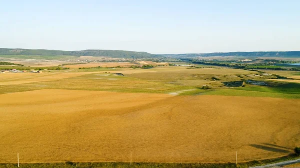 Top view of yellow fields on background of village on horizon. Shot. Beautiful landscape with agricultural yellow fields and village in distance — Stock Photo, Image