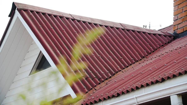 Wellblechdach. Archivmaterial. Details des roten Daches aus Metallprofil gefertigt und abgedeckt. Nahaufnahme der Dacheindeckung von den Schrägen der Seitenfenster — Stockfoto