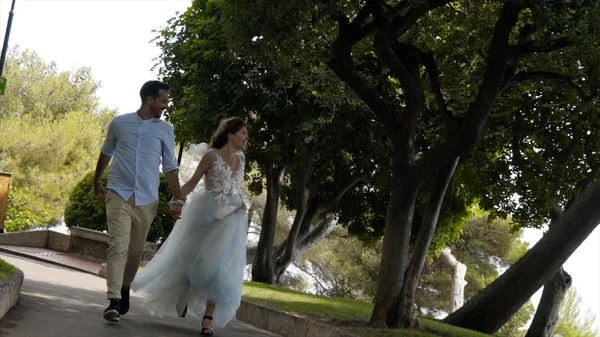 Yeşil Park 'ta koşuşturan mutlu çift. Başla. Güneşli bir parkta koşuşturan güzel yeni evliler. Genç karı koca gülümseyen koşu parkı