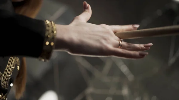 Jonge aantrekkelijke vrouw hand vasthouden drumstick en draaien tijdens de muzikale repetitie. Actie. close-up voor vrouw hand met manicure en gouden ringen houden en spinnen een drumstick. — Stockfoto