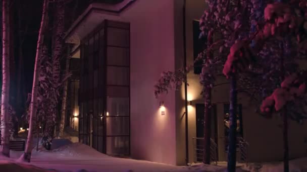 Fasada duży dom późny zimowy wieczór oświetlony kolorowy migający światło awaryjny samochód. Materiał filmowy. Widok na zewnątrz domku w śnieżnej zimie w nocy. — Wideo stockowe