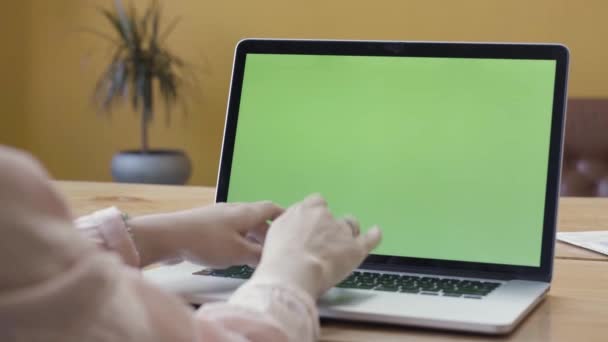녹색 화면이 달린 랩탑을 사용하는 한 여성의 어깨 너머의 모습. 주가 영상이요. 여자 손 이 노트북 키보드, 색소폰 사업, 의사소통, 프리랜서, 인터넷 개념 위에 타자를 치는 모습 — 비디오
