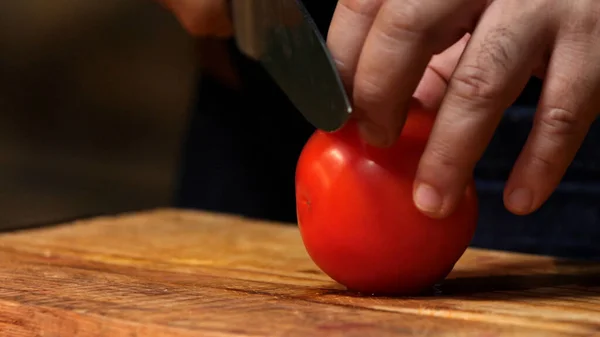 Rote Tomaten auf Holzbrett schneiden. Archivmaterial. Koch schneidet Tomaten auf einem Holzbrett — Stockfoto