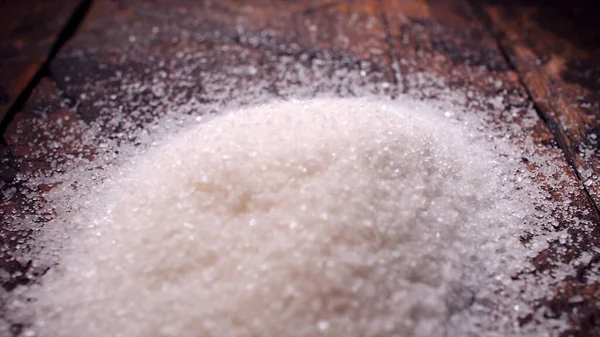 Sucre en granulés sur une surface brun bois. Images d'archives. Une diapositive de sucre avec du sable sur la table — Photo