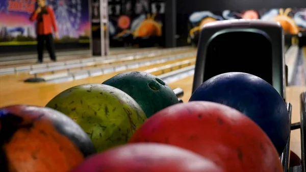 Primo piano di un giovanotto che prende palle da bowling dal rack. I media. Competitivi amici allegri giocare a bowling insieme nel club — Foto Stock