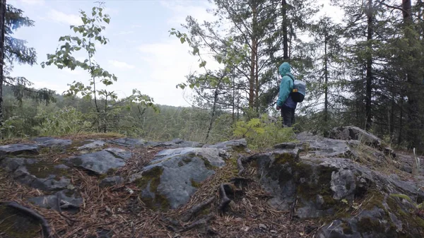 Wanderer mit Rucksack vom Waldrand, Erlebnis- und Reisekonzept. Archivmaterial. bärtiger Mann in hellblauer Jacke besteigt den Berg im Wald. — Stockfoto