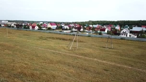 Luftaufnahme von Hüttendorf in der Nähe des leeren Feldes für zukünftige Gebäude im Spätsommer vor blauem bewölkten Himmel. Archivmaterial. schöne Landschaft — Stockvideo