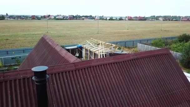 Luchtfoto van luxe huisje met rood dak in het huisje nederzetting in de buurt van het lege veld voor toekomstige gebouw in de zomer tegen blauwe bewolkte hemel. Voorraadbeelden. Prachtig landschap — Stockvideo