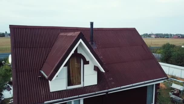 Luftaufnahme von Luxus-Ferienhaus mit rotem Dach in der Hüttensiedlung in der Nähe des leeren Feldes für zukünftige Gebäude im Sommer vor blauem bewölkten Himmel. Archivmaterial. schöne Landschaft — Stockvideo