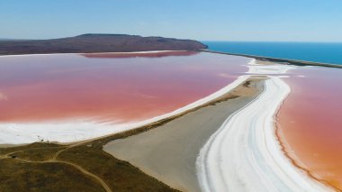 Parlak renkli, ünlü doğal yerin panoramik hava manzarası. Kırım 'da muhteşem bir kıyı şeridi ve arka planda turkuaz deniz bulunan pembe bir göl. Vuruldu. Tuz beyaz kıyıları olan eşsiz pembe göl..