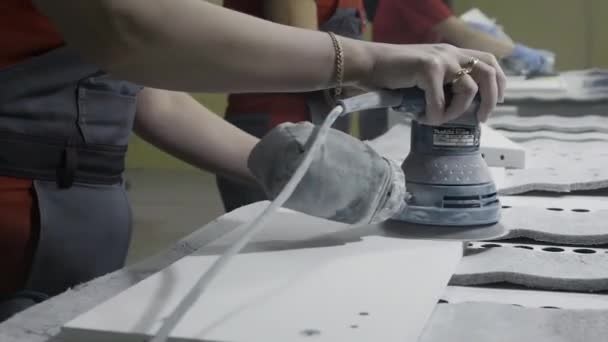 Nahaufnahme von Arbeitern, die das Holz mit einer Winkelschleifmaschine schleifen. Aktion. Menschen in der Werkstatt arbeiten mit weißen Holzplatten mit Poliermaschine. — Stockvideo