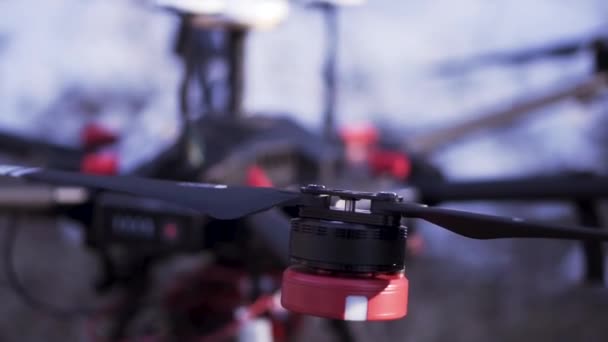 Detailní záběr červené a černé quadcopter stojící na zemi připraven pro let a video natáčení, moderní technologie koncept. Klip. Nový dron s kamerou na rozmazaném pozadí. — Stock video