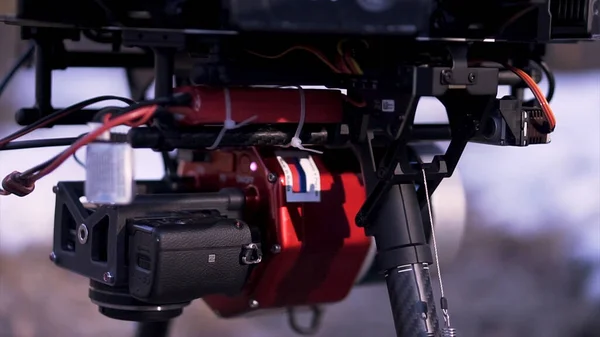 Close up de quadricóptero vermelho e preto em pé no chão pronto para o voo e filmagem de vídeo, conceito de tecnologias modernas. Clipe. Novo drone com câmera no fundo embaçado . — Fotografia de Stock