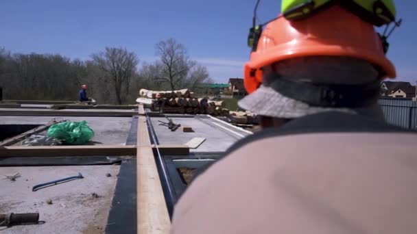 Gros plan du travailleur de la construction debout sur le toit de la maison avec ruban à mesurer. Clip. Éléments de mesure homme charpentier avec roulette de construction . — Video