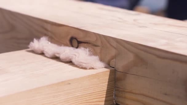 Gros plan de deux poutres en bois croisées pour construire une maison sous le soleil. Clip. Partie de la construction en bois avec isolation thermique blanche . — Video