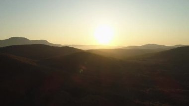 Gün batımında gökyüzünün altındaki devasa yeşil dağların havadan görünüşü. Vuruldu. Birçok tepe açık günbatımı arka planında yeşil ağaçlarla kaplı..