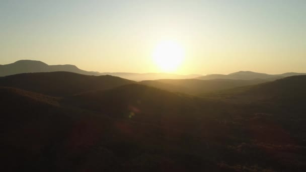 Αεροφωτογραφία των όμορφων τεράστιων πράσινων βουνών κάτω από το ηλιοβασίλεμα. Πυροβολήθηκε. Πολλοί λόφοι καλύπτονται από πράσινα δέντρα σε καθαρό ηλιοβασίλεμα ουρανό φόντο. — Αρχείο Βίντεο