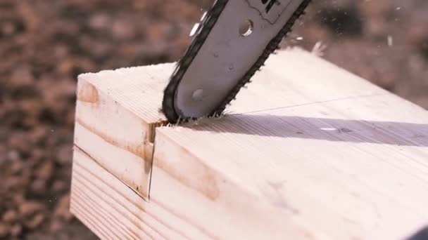 Nahaufnahme des Arbeiters mit einer elektrischen Säge, die Holzbalken schneidet, wobei Späne und Staub in die Seiten fliegen. Clip. Zimmermannsarbeit, Holzbalken mit der Säge schneiden.