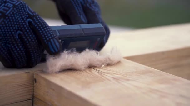 Nahaufnahme von Arbeiterhänden in blauen Handschuhen, die Laserwaage auf den Holzbalken legen, moderne Holzhauskonstruktion. Clip. Bulder Messpegel mit der Spezialausrüstung. — Stockvideo