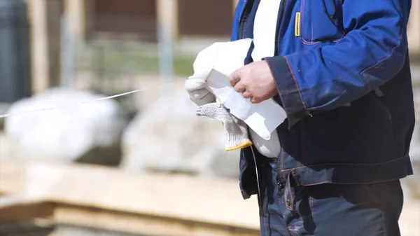 Close up de trabalhador de construção em pé no telhado da casa com fita métrica. Clipe. Carpinteiro homem elementos de medição com roleta de construção . — Fotografia de Stock