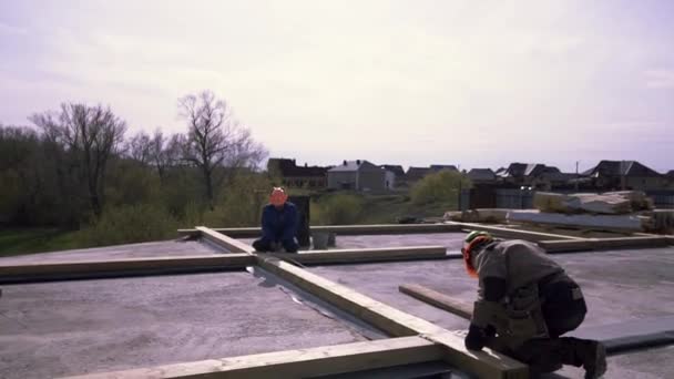 Framing Crew Dach Vorbereitung Holzkonstruktion, Messung für eine bessere Genauigkeit. Clip. Arbeiter stehen auf dem Flachdach des Gebäudes und messen Holzbalken mit Klebeband.