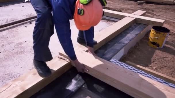 Close up of a carpenter holding a wooden beam and putting it down inside the hole of anothe beam. Clip. Details of joints and heating insulation for holding wooden frame structure together. — Stock Video