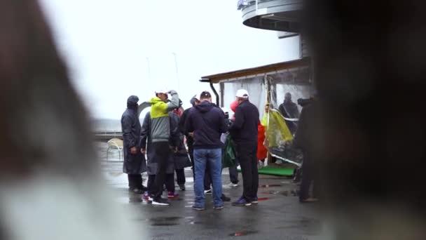 Visão traseira do grupo adulto de pessoas em capas de chuva em pé perto do lago no final do outono. Arte. Turistas homens e mulheres perto do lago em tempo frio, camping viagem e conceito de estilo de vida ativo . — Vídeo de Stock