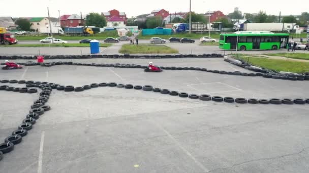 Kart racers in protective uniform and helmet moving on the track with old black car tires in the city in sunny day. Media. Karting Championship — Stock Video