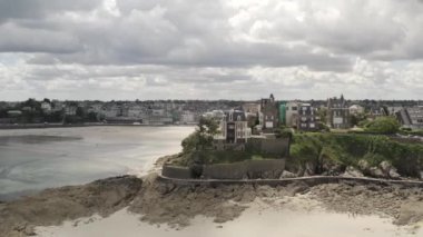 Yazın gri bulutlu gökyüzüne karşı kumlu nehir kenarındaki gri Avrupa şehrinin güzel hava manzarası. Başla. Muhteşem Avrupa mimarisi