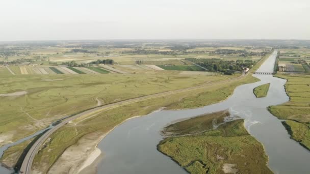 Luchtfoto van grote rivier omgeven door landbouwvelden tegen grijze bewolkte lucht. Actie. Luchtfoto van het platteland. — Stockvideo