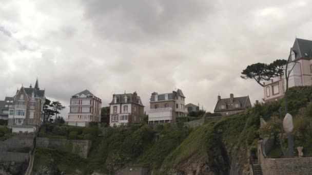 Blick von unten auf die tollen modischen Ferienhäuser, die im Sommer am Hang vor grauem wolkenverhangenem Himmel stehen. Aktion. schöne europäische Architektur — Stockvideo