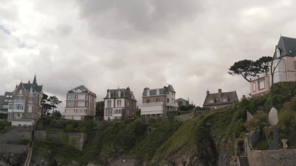 Vista desde la parte inferior de las impresionantes cabañas de moda de pie en la cima de la pendiente en verano contra el cielo gris nublado. Acción. Hermosa arquitectura europea — Vídeos de Stock