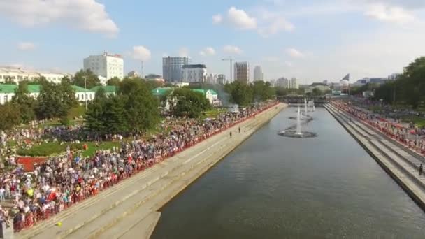 Vista aérea de muitas pessoas andando no aterro com fontes no dia quente de verão contra o céu azul nublado. Acção. Vida de verão da grande cidade — Vídeo de Stock