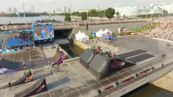 Luftaufnahme eines Rad- und Motorrad-Freestyle-Wettbewerbs in einer großen russischen Stadt in der Nähe des Dammes bei warmem, sonnigem Tag. Aktion. Menschen beim Fahrradfest — Stockvideo