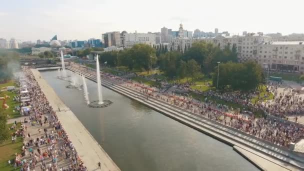 Повітряний вид великої кількості людей йде по набережній з фонтанами в теплий літній день проти блакитного хмарного неба. Почали. Літо у великому місті. — стокове відео