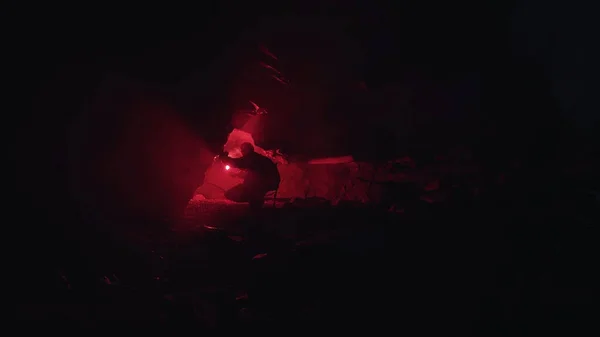 Jeune homme avec une éruption de signal rouge brûlant dans sa main venant au trou étroit dans la grotte souterraine sombre. Images d'archives. Tourisme explorant tunnel mystérieux . — Photo