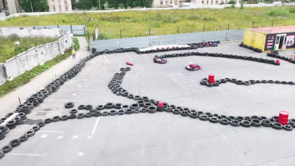 Légi kilátás gokart versenyzők védő egyenruhában és sisak mozog a pályán a régi fekete autó gumiabroncsok a városban a napsütéses napon. A média. Karting Bajnokság — Stock videók