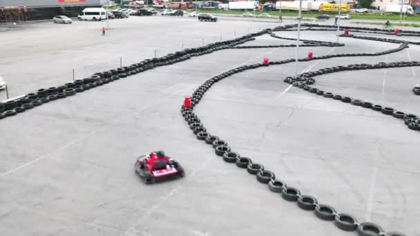 Kart racers in beschermende rode uniform en helm bewegen op de baan met oude zwarte autobanden. De media. Kart rijopleiding. — Stockvideo