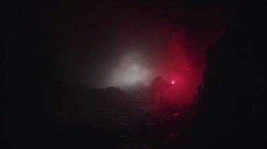 Karanlık mağarayı inceleyen bir jeologun silueti, kırmızı işaret fişeği taşıyor. Stok görüntüleri. Taş gibi eski tünel, doğa ve paleontoloji kavramını araştıran bilim adamı..