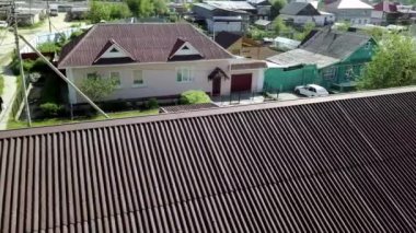 Köyün arka planında yeni bir çatı var. Stok görüntüleri. Köy evlerinin arka planındaki yeni çatının tepe manzarası. Kır evinin modern koyu çatısı