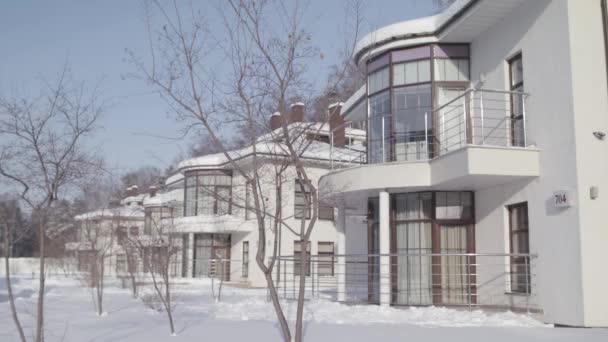 Winter landschap met huisjes staan in een rij van witte kleur op de achtergrond van de blauwe lucht. Voorraadbeelden. Moderne mooie huizen in besneeuwde winter. — Stockvideo