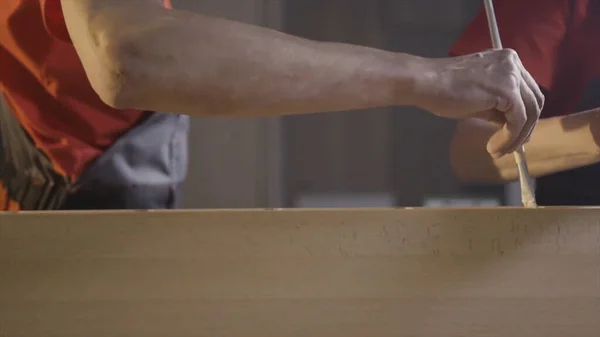 Primer plano de dos captadores machos extendiendo el adhesivo sobre las superficies de unión. Acción. Manos de trabajador aplicando pegamento a una viga de madera . —  Fotos de Stock