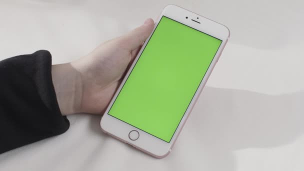 흰색 배경에 터치 스크린 스마트 폰을 들고 있는 것입니다. 주가 영상이요. 크로마 키와 휴대폰을 가지고 손을 잡고. — 비디오