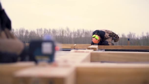 Close up do nível de medição a laser para obras de construção em pé em uma barra de madeira no canteiro de obras. Clipe. Construtores masculinos fazendo quadro . — Vídeo de Stock