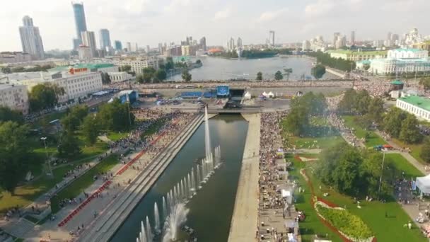 Vista aérea de muitas pessoas andando no aterro com fontes perto do rio em dia quente de verão contra o céu azul nublado. Acção. Vida de verão da grande cidade — Vídeo de Stock